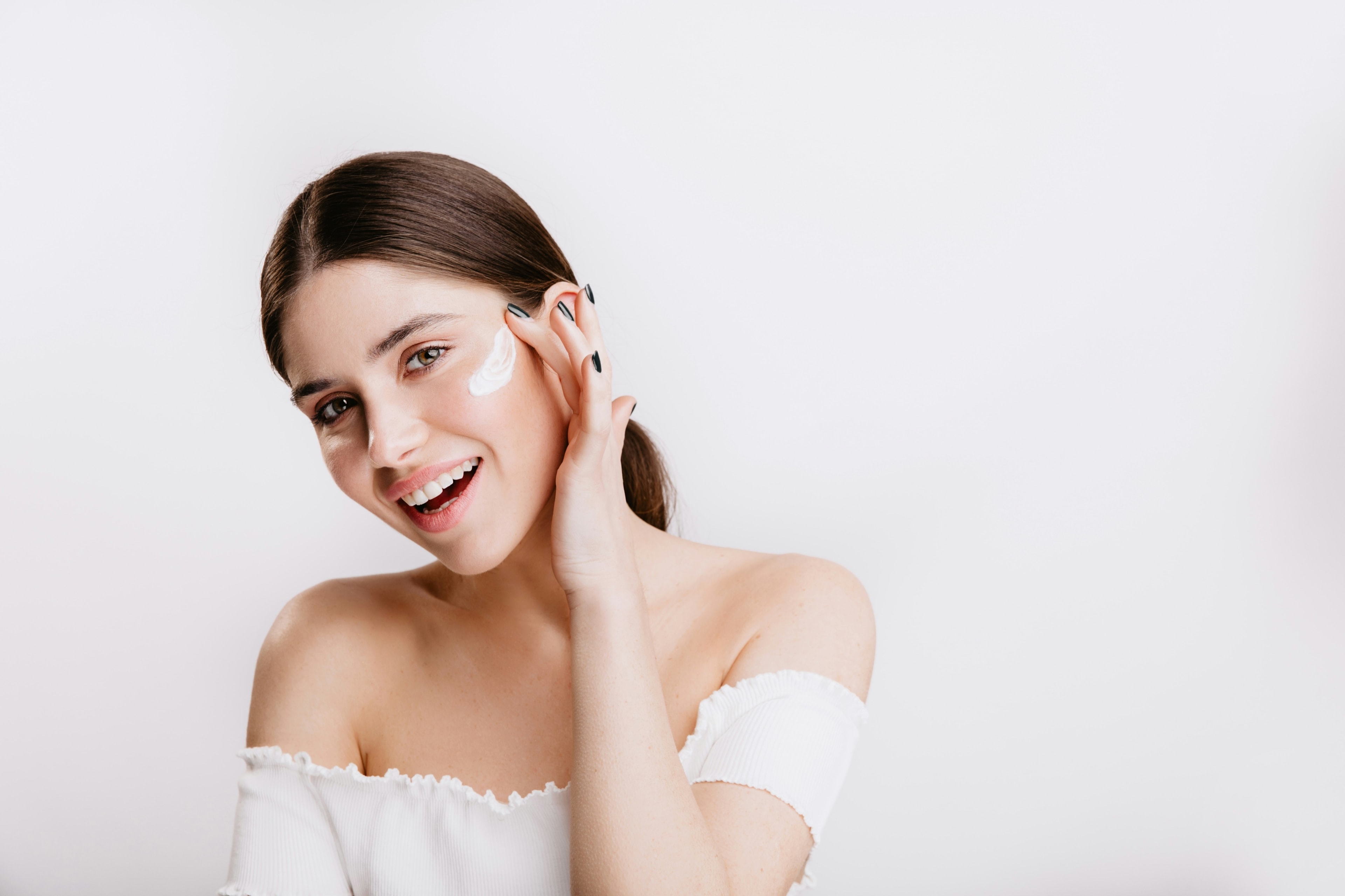 A smiling woman in a white shirt, hand resting near her face